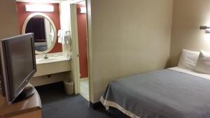 a bedroom with a bed and a sink and a mirror at Days Inn by Wyndham Buena Park in Buena Park