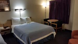 a hotel room with a large bed and a table at Days Inn by Wyndham Buena Park in Buena Park