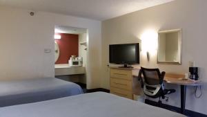 a hotel room with a bed and a desk with a television at Days Inn by Wyndham Buena Park in Buena Park