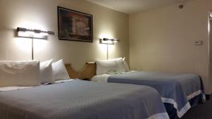 two beds in a hotel room with two lamps at Days Inn by Wyndham Buena Park in Buena Park