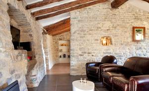 a living room with leather furniture and a stone wall at Domaine de Monteils in Carnas