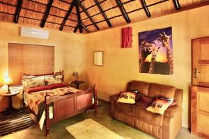 a bedroom with a bed and a couch at Hyenas Call in Marloth Park
