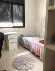 a bedroom with a bed and a desk and a window at Quarto em casa com lazer completo in Indaiatuba