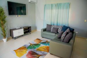 uma sala de estar com um sofá e uma televisão de ecrã plano em Beautiful Village 3 bedrooms Furnished Pool residencial Velero punta cana em Punta Cana