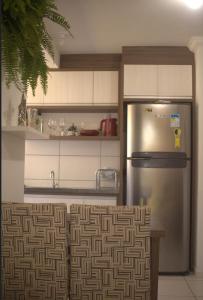 uma cozinha com um frigorífico de aço inoxidável e armários brancos em Apartamento de Praia em Florianópolis
