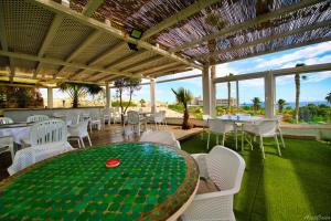 un restaurante con una mesa verde y sillas blancas en Waves of Tranquility Residence, en San Miguel de Abona