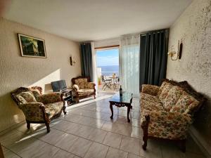 een woonkamer met banken en een tafel en een balkon bij TABAIBA REFUGIO DEL MAR in Santa Cruz de Tenerife