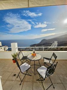 una mesa y sillas en un balcón con vistas al océano en TABAIBA REFUGIO DEL MAR, en Santa Cruz de Tenerife