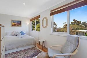 a bedroom with a bed and a chair and a window at Kookaburra Hideaway 4-Bed 2-Bath in Cowes