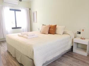 a white bed with towels on it in a bedroom at Complejo Koi in General Alvear