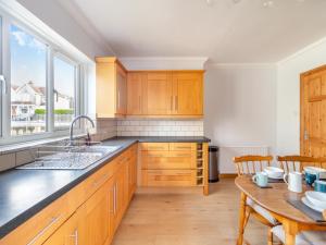 a kitchen with wooden cabinets and a table and a window at Ty Cwtch in Seven Sisters
