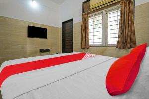 um quarto com uma cama grande com almofadas vermelhas e uma televisão em OYO Flagship Raj Hotel Near Juhu Beach em Mumbai