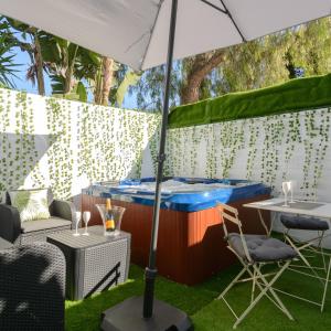 a table and chairs with an umbrella in the grass at Malaga Chic jacuzzi y playa in Málaga