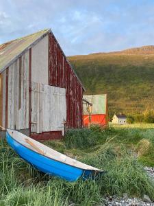 a boat sitting in the grass next to a barn at Hos Laura & Valdemar in Nord-Lenangen