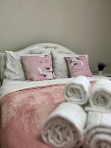 Una cama con almohadas rosas y blancas. en Квартира Rose, en Öskemen