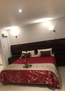Un dormitorio con una cama roja con un jarrón. en HOTEL CB CAJAMARCA HUACARIZ, en Cajamarca
