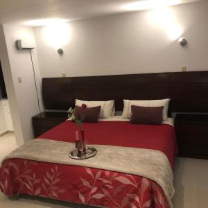 um quarto de hotel com uma cama com uma colcha vermelha em HOTEL CB CAJAMARCA HUACARIZ em Cajamarca