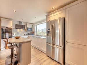 a kitchen with a stainless steel refrigerator and a table at Wynmine Cottage in Esh