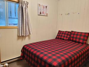 Cama a cuadros rojo y negro en una habitación en Birch Cabin: Lakefront Hideaway Resort - 3 bedroom, en Kawartha Lakes
