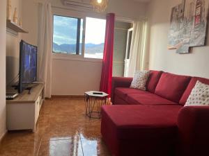 een woonkamer met een rode bank en een tv bij Melo Home Vecindario-Near AirPort-Elevator-Garage in Sardina