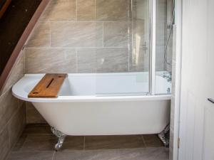 a bathtub with a wooden board on top of it at The Old School House 1-uk32061 in Burwarton