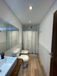 uma casa de banho com um WC, um lavatório e um espelho. em Disfruta de Pinamar en un departamento a estrenar con pileta y parrilla em Pinamar