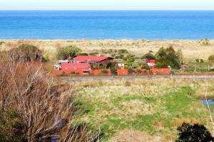 a farm with red buildings and the ocean in the background at Hapuku Carriages Kaikōura in Kaikoura