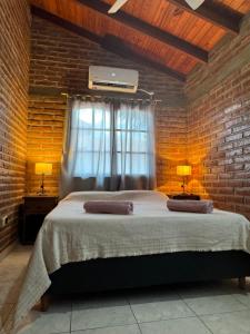 1 dormitorio con 1 cama grande y pared de ladrillo en Cabaña en el Centro de Mina Clavero en Mina Clavero
