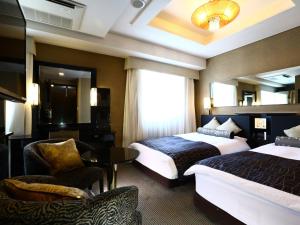 a hotel room with two beds and a chair at APA Hotel Higashi Shinjuku Kabukicho in Tokyo