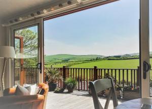 a balcony with a view of a green field through a sliding glass door at Bossiney Bay in Tintagel