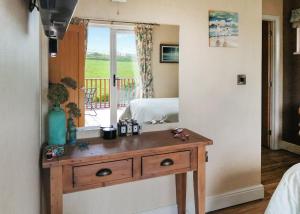 a bedroom with a wooden dresser and a bed with a window at Bossiney Bay in Tintagel