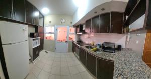 a kitchen with black cabinets and a white refrigerator at Humberto Apart A in Luján