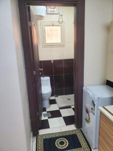 a bathroom with a toilet and a black and white tile floor at شقق عنوان المدينة للوحدات السكنية in Medina