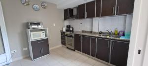 a kitchen with brown cabinets and a microwave oven at Humberto Apart B in Luján