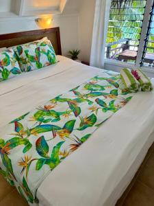 a bed with a white comforter with colorful butterflies at Paradise Cove Lodge in Arutanga