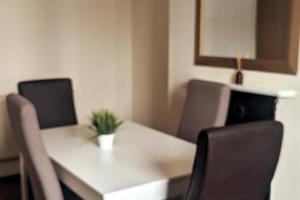 uma mesa branca com cadeiras e um vaso de plantas sobre ela em Welcoming Flat By Kasar Stays em Gillingham