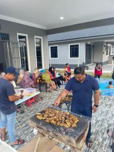 Ein Mann kocht Essen auf einem Grill in der Unterkunft Homestay Kuala Dungun in Dungun