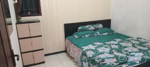 a bedroom with a bed with a green comforter and pillows at Azalea Homestay in Batu