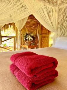 una pila de toallas rosas sentadas encima de una cama en Treehouse waterfalls El Limón D-03 en El Limón