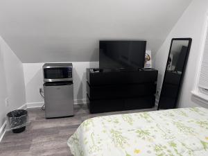 a bedroom with a bed and a microwave and a television at Modern & cozy Room in Queens near Train station and buses in Woodhaven