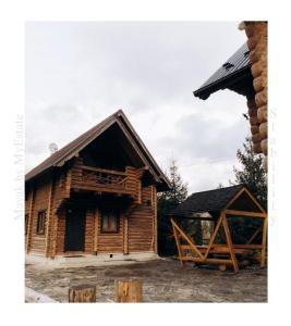 a log cabin with a porch and a building at Mayak Chalet Resort Mykulychyn in Mykulychyn
