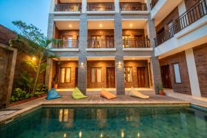 a villa with a swimming pool in front of a building at Gelatik Bed And Breakfast in Seminyak