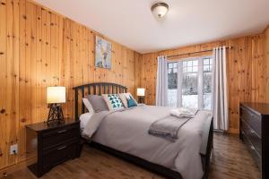 a bedroom with a bed with wooden walls and a window at Chalet le Boréal: Massif, spa et montagnes in Petite-Rivière-Saint-François