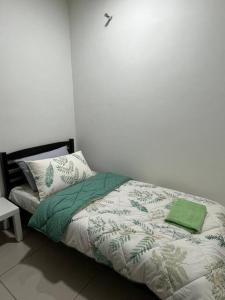 una camera da letto con un letto con una coperta e cuscini verdi di Rafahiyyah Homestay, Puncak Alam a Kuala Selangor