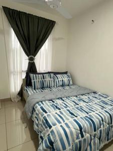 una camera da letto con un letto con lenzuola blu e bianche e una finestra di Rafahiyyah Homestay, Puncak Alam a Kuala Selangor