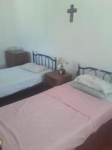 2 camas en un dormitorio con una cruz en la pared en Casita en Ticuman, en Ticumán