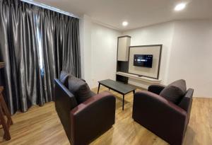 sala de estar con 2 sillas y TV de pantalla plana en The Executive Apartment @ Kuching City Mall, en Kuching