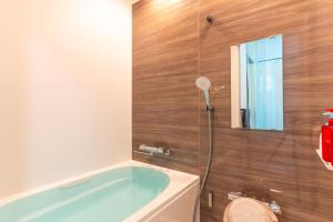 a bathroom with a bath tub and a toilet at FuranoSky - White in Furano