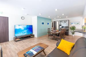 a living room with a couch and a tv and a table at FuranoSky - White in Furano