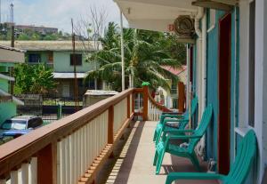 un balcón con sillas verdes en una casa en Hilltop Horizon Guesthouse, en San Ignacio